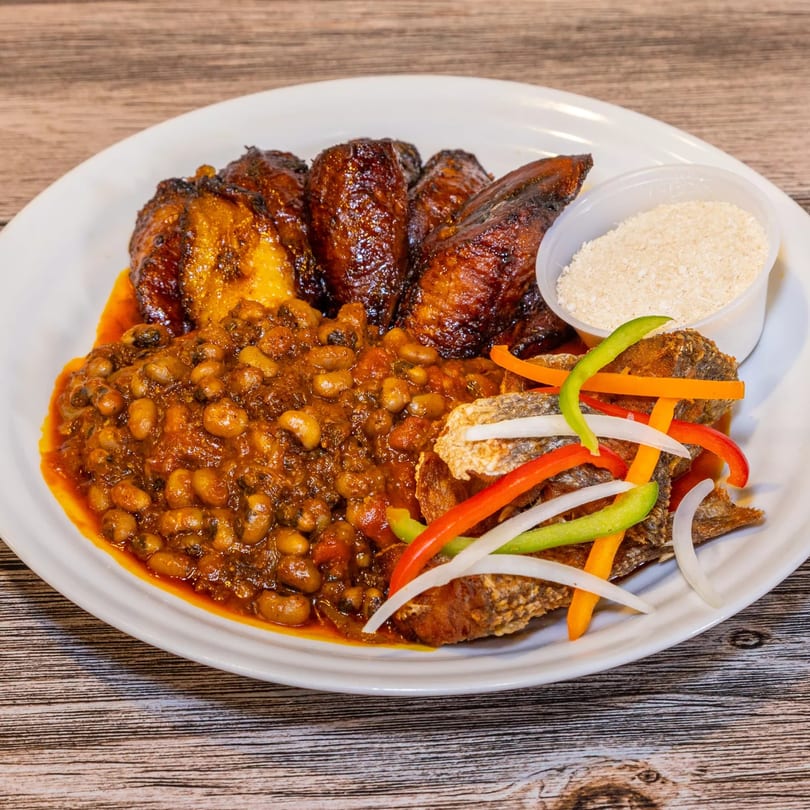 Dalia's African Cuisine plate with fried plantains, beans in sauce, fried fish, and a side of gari.