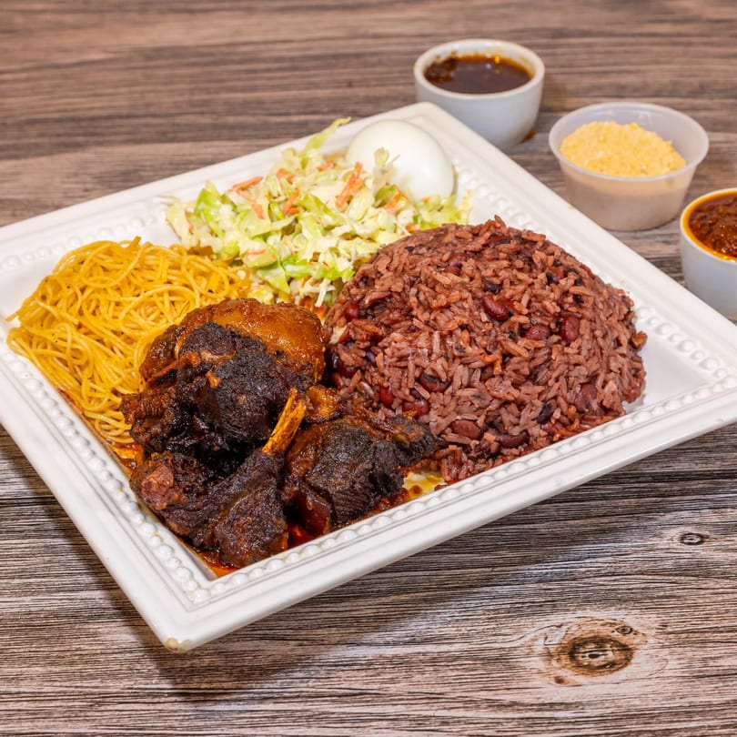 Dalia's African Cuisine meal with dark meat, red rice, noodles, coleslaw, and a hard-boiled egg.