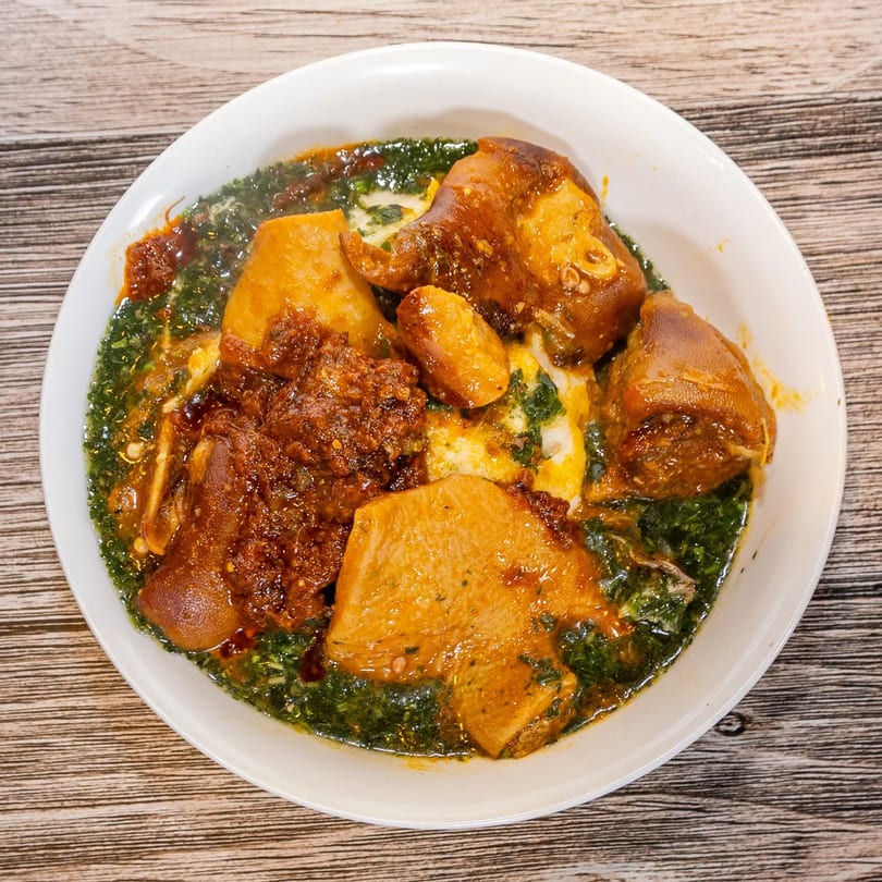 Dalia's African Cuisine dish with meat, green stew, and orange sauce in a white bowl.